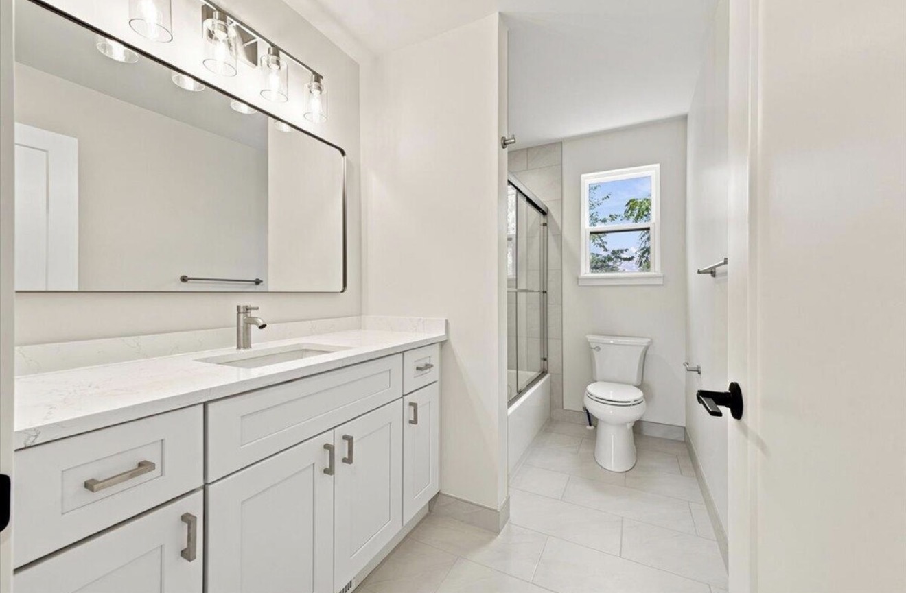 Secondary bathroom with quartz vanity and tiled bath